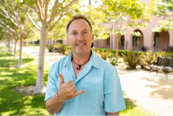 Ken Rosenthal smiling at the camera and giving the shaka or "hang loose" sign, while standing outside