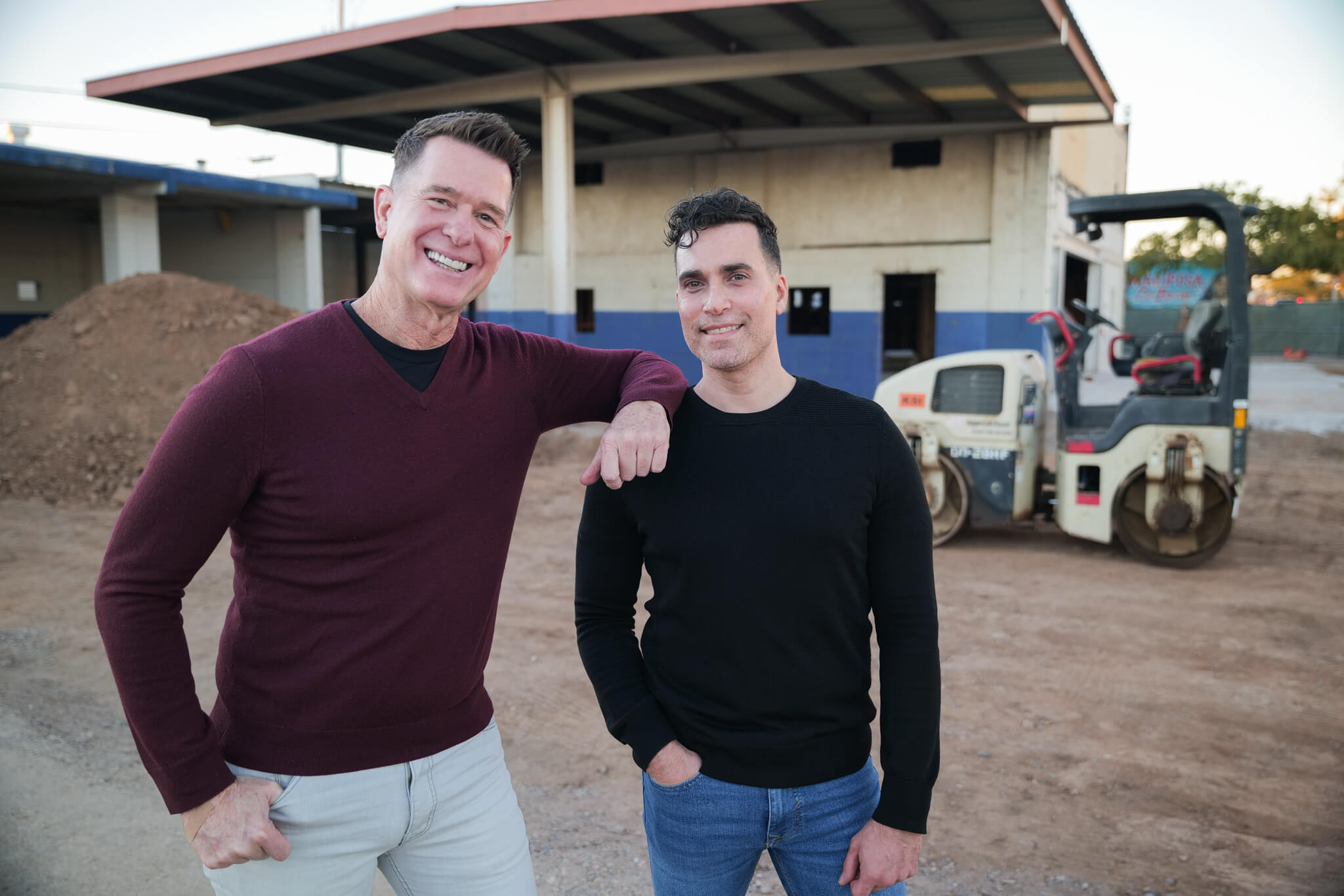 Two entrepreneurs stand proudly in front of their construction project.