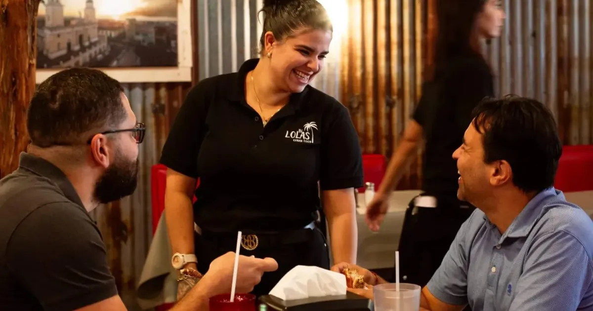 Lola's Cuban Restaurant customers at a table with an entrepreneur store owner who received a SBA 7(a) Community Advantage loan from CDC Small Business Finance.