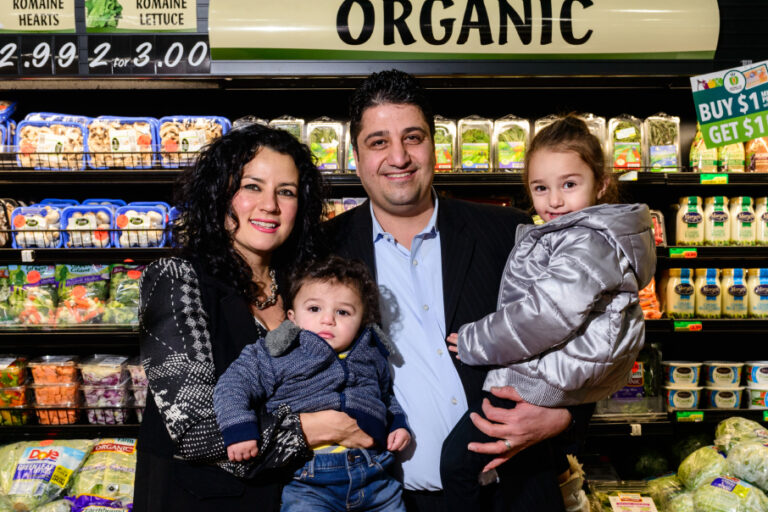 A family poses in front of a produce section at the supermarket.