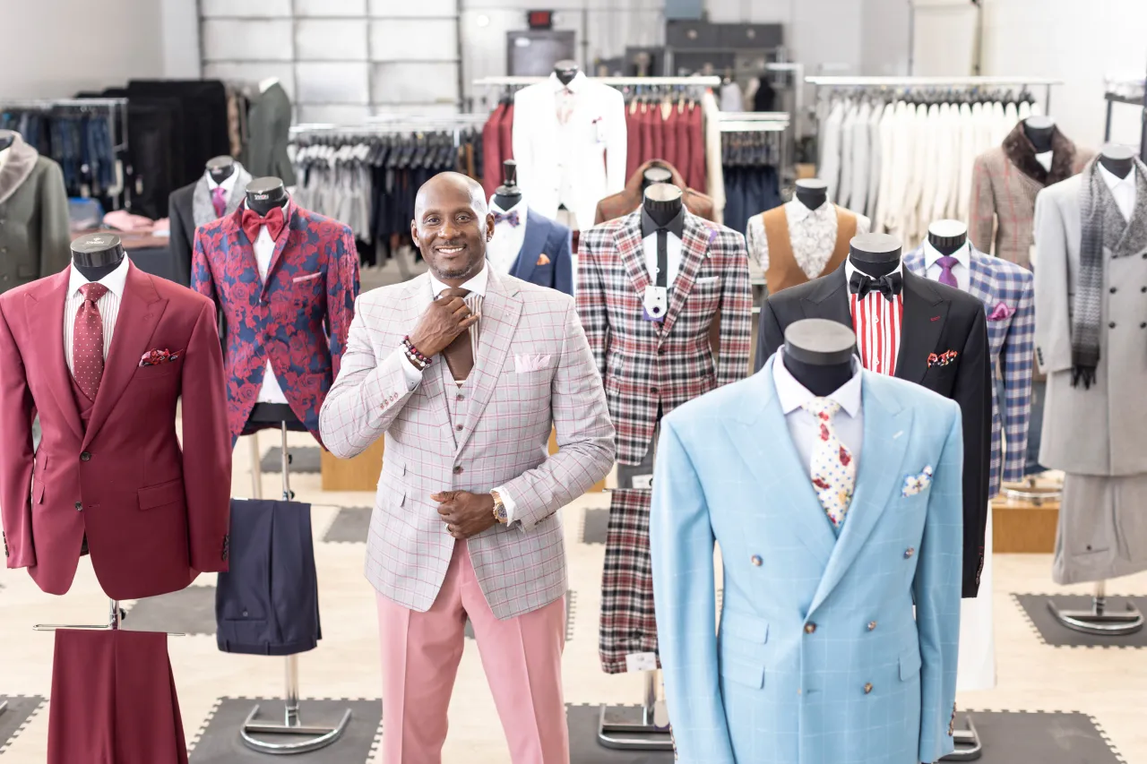 Montee adjusts his tie surrounded by suits displayed in his workspace after receiving impact investment financing from Momentus Capital.