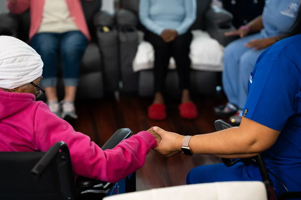 A woman in a wheelchair holding hands with her caretaker at Hope House, a haven of unity and inclusivity.