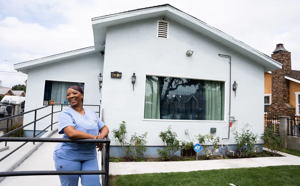 A dedicated healthcare professional in scrubs stands outside a house, ready to provide care and support.