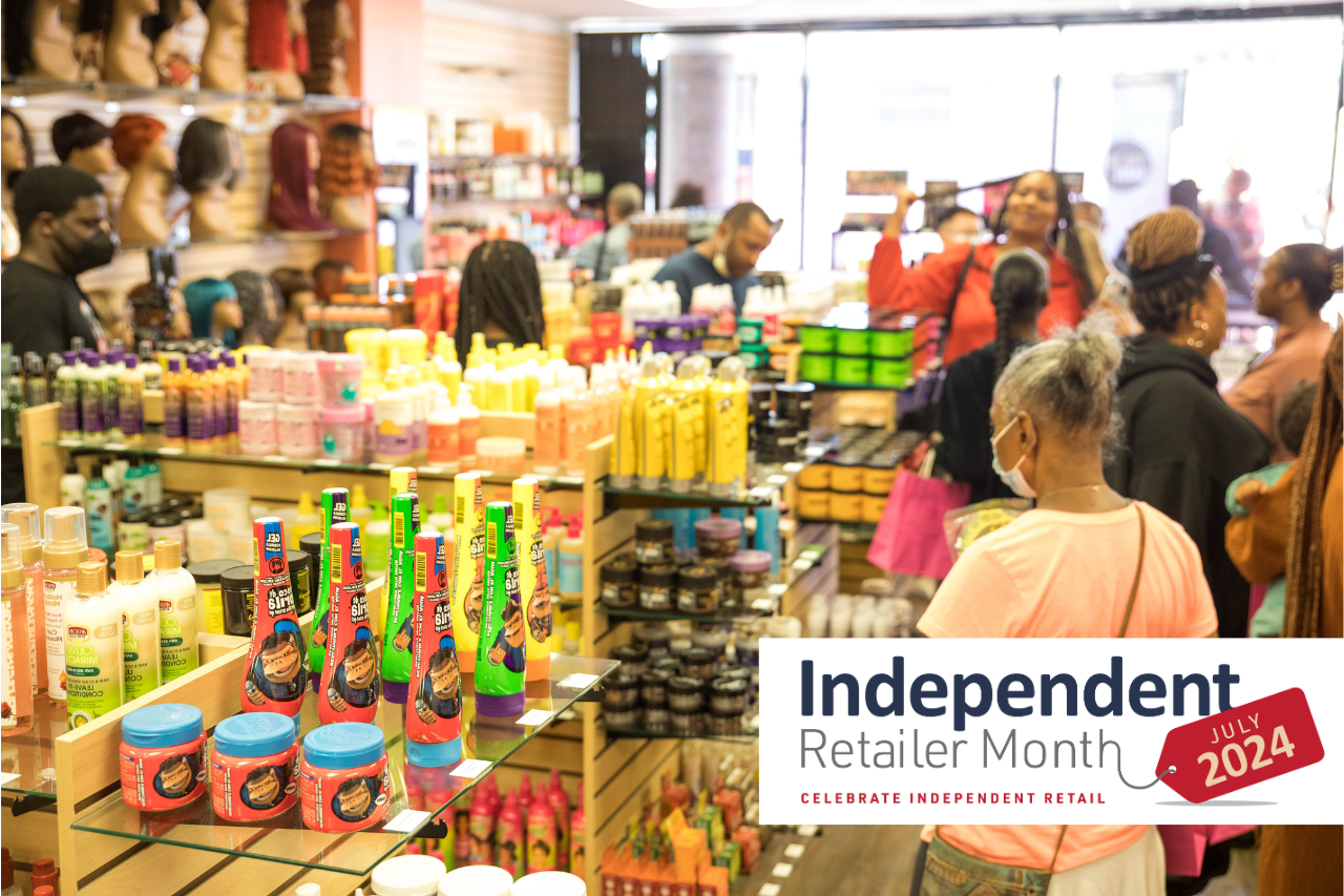 Inside a crowded retail store during its grand opening and an Independent Retailer Month 2024 banner.