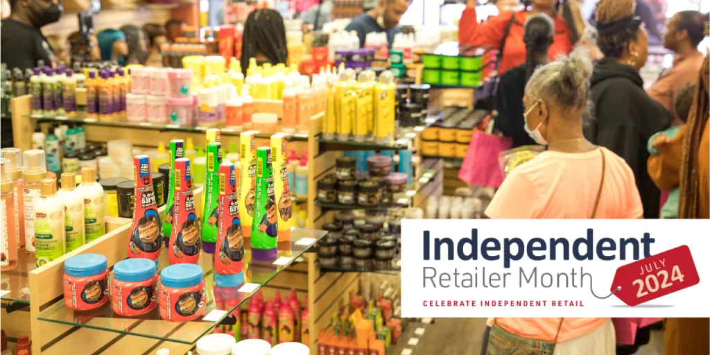 Inside a crowded retail store during its grand opening and an Independent Retailer Month 2024 banner.