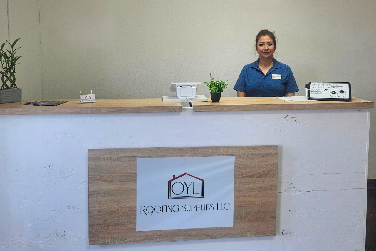 Esmeralda Polanco stands behind a reception desk, smiling and ready to assist visitors, a key to small business success.