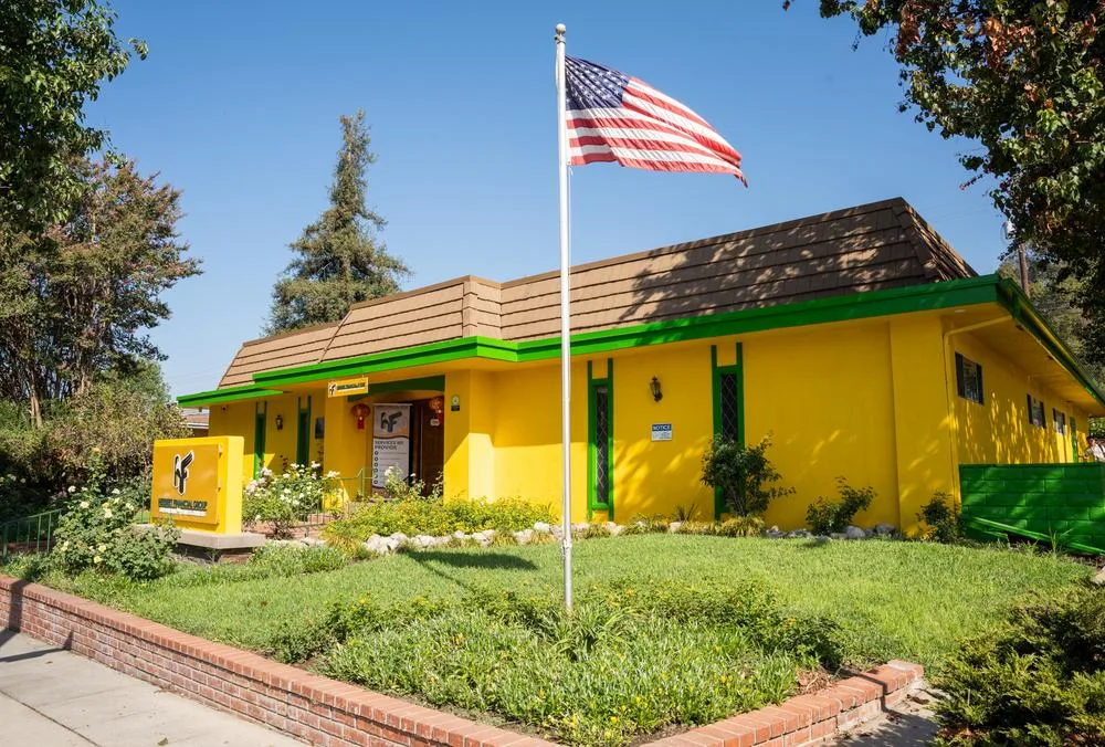 Herbert Financial Group's new office is in a bright yellow and green building, this picture shows a beautiful SoCal sunny day and an American flag waving gently in the breeze.