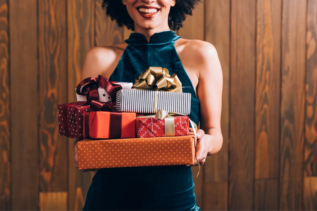 CDC 2024 Holiday Gift Guide - Featured image, a young black woman comes bearing gifts.