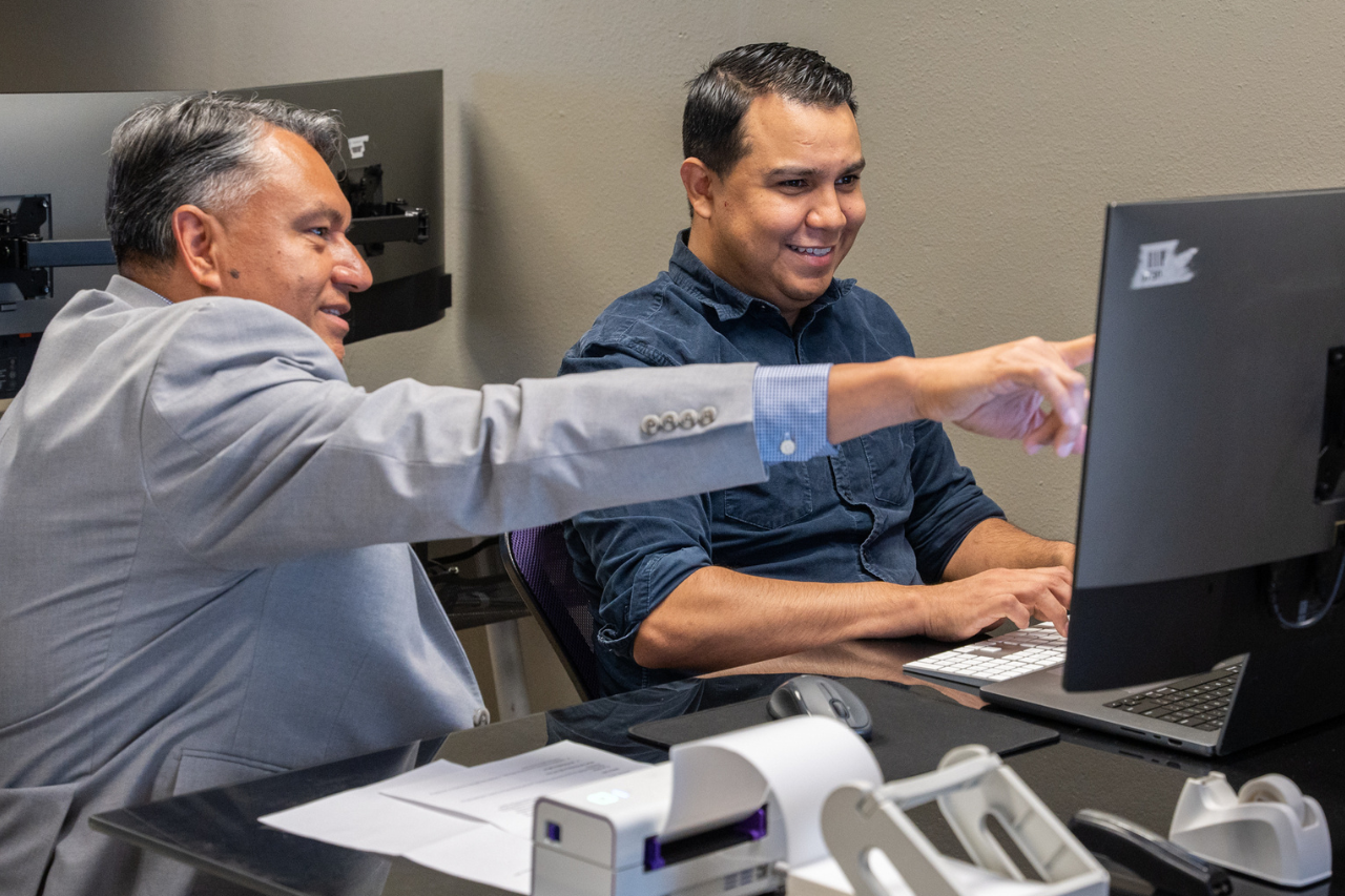 Computer station access with business advising services. Osbaldo helps a young entrepreneur with his business plan.