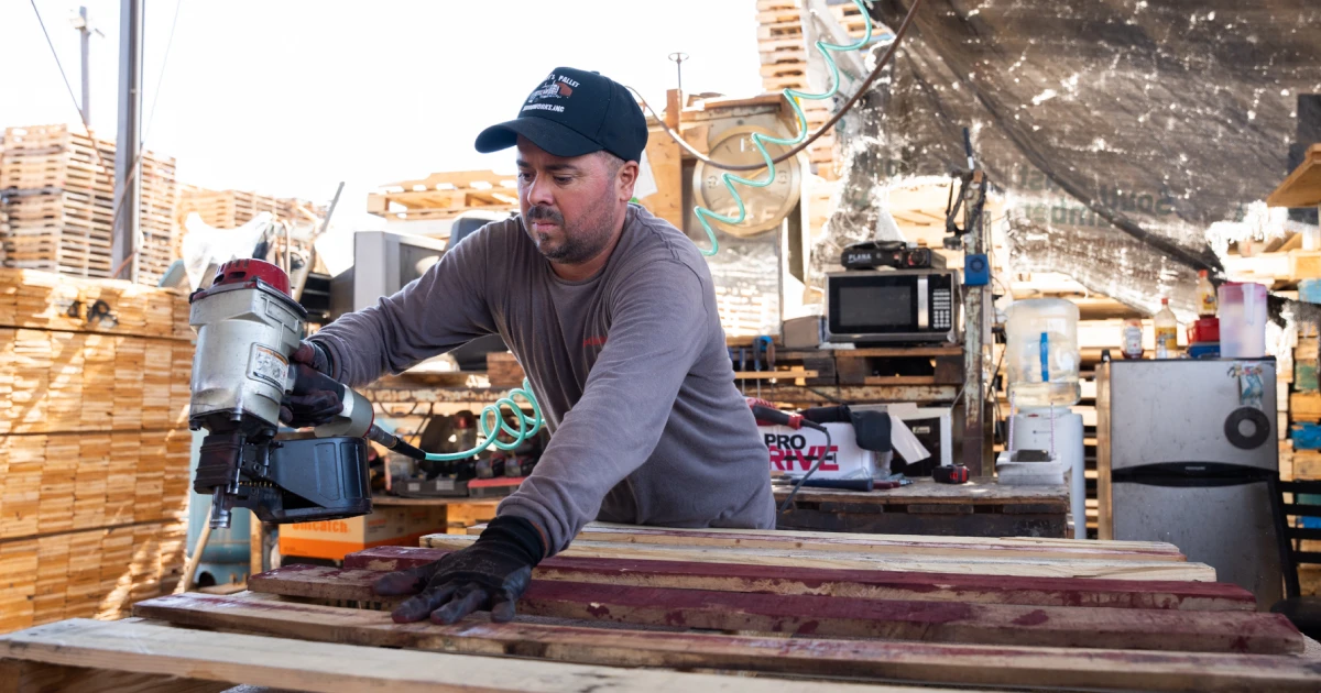 Man builds pallets at Johnny’s Palletworks; SBA manufacturing fee reduction can positively affect manufacturing businesses.