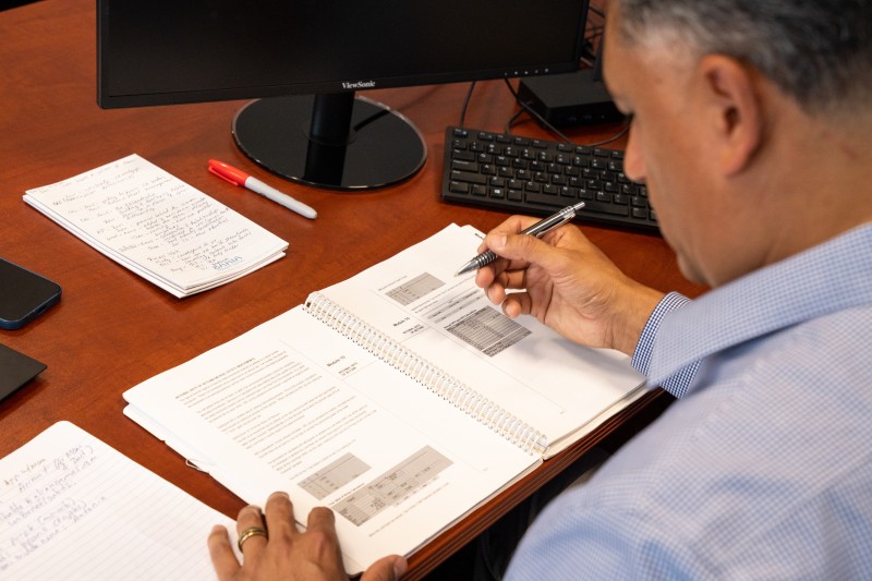 A man is engaged in writing financial information on paper, surrounded by a calm and organized workspace.