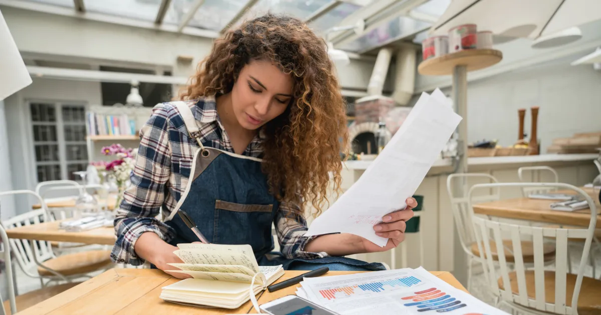 Business owner looking at charts and taking notes in a notebook, comparing the costs of leasing versus buying commercial property