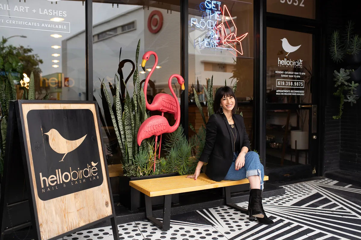 A woman sits on a bench outside her salon, made possible with an SBA loan for salon suite business