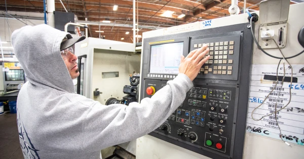Waterstone Faucets employee operating a CNC machine control panel at a manufacturing facility in Murrieta, California.
